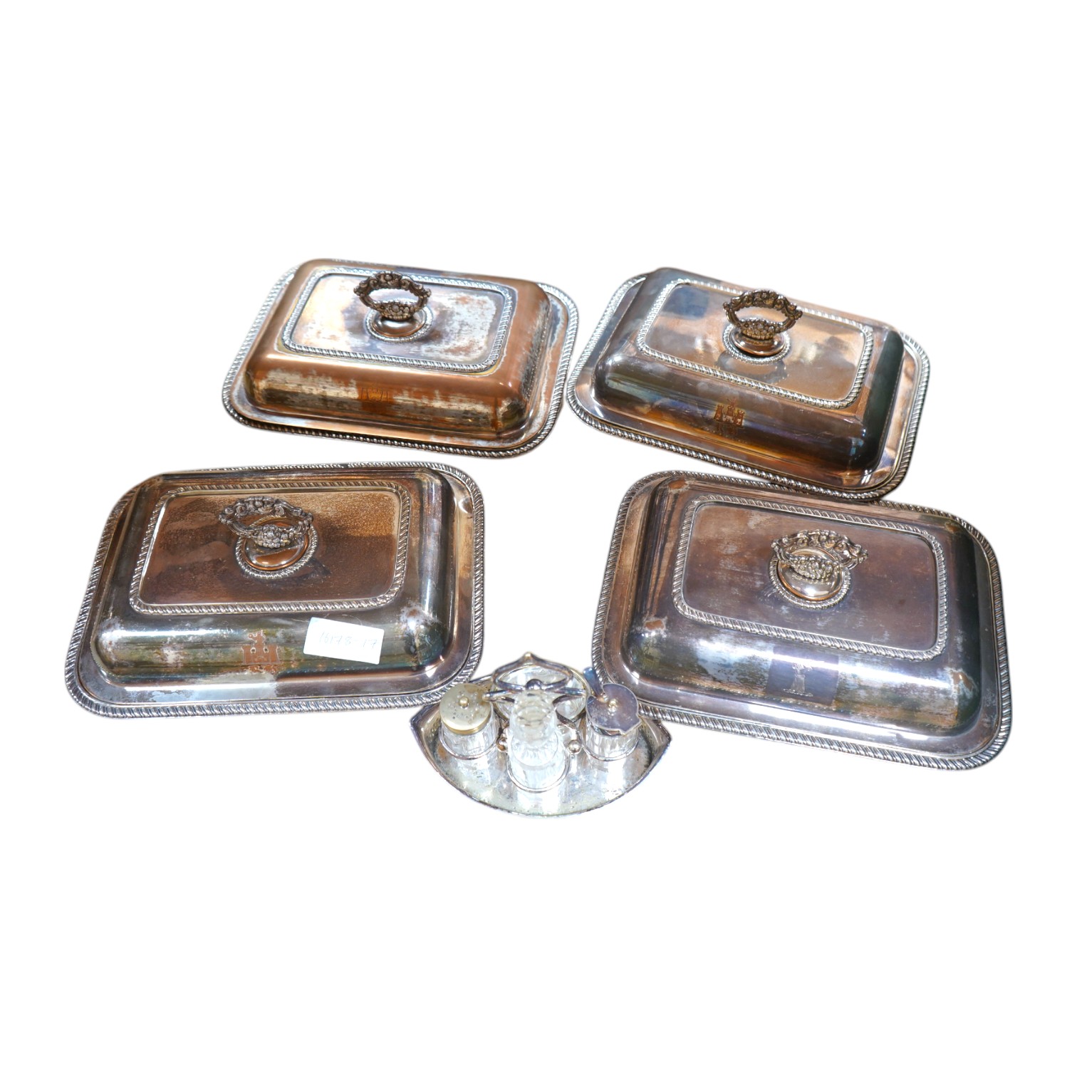 A set of four silver plated entrée dishes and covers and a plated four piece condiment stand, largest entree dish 22cm wide, 29cm long. Condition - plate worn